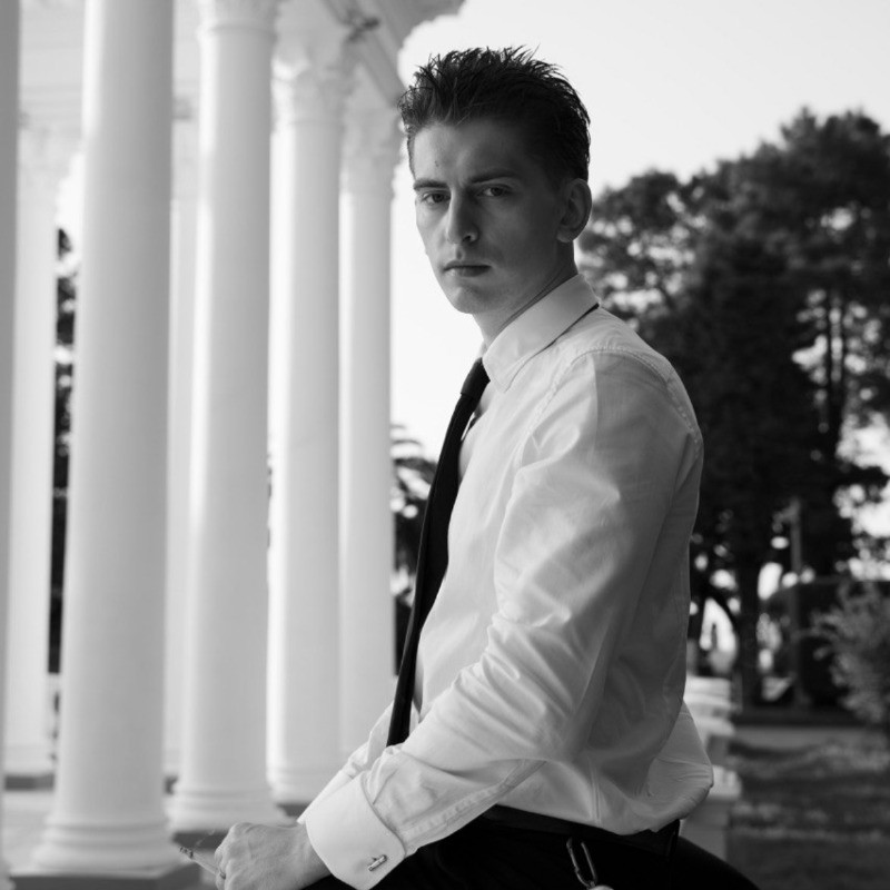 Ivan Gribin, black-and-white portrait beside a row of white columns